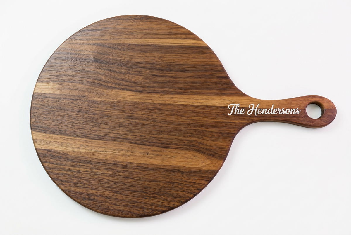 Walnut pizza serving board with white epoxy-filled The Hendersons engraving on the handle